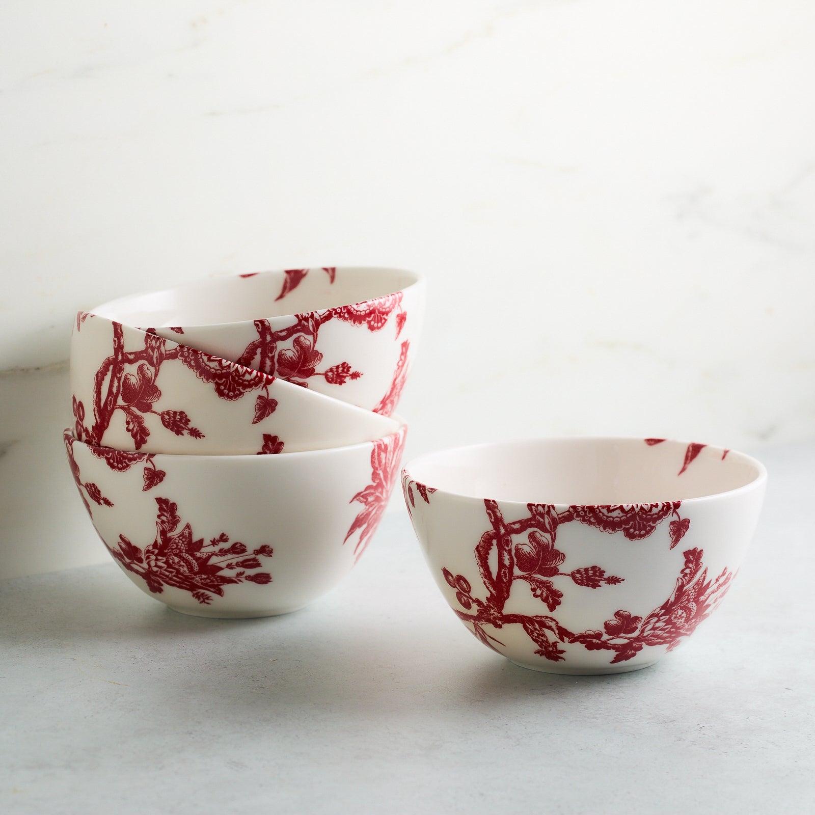 A premium porcelain dinnerware piece, this white cereal bowl features a stunning red floral and bird pattern design, inspired by the Williamsburg Foundation. Introducing the Arcadia Crimson Cereal Bowl by Caskata.