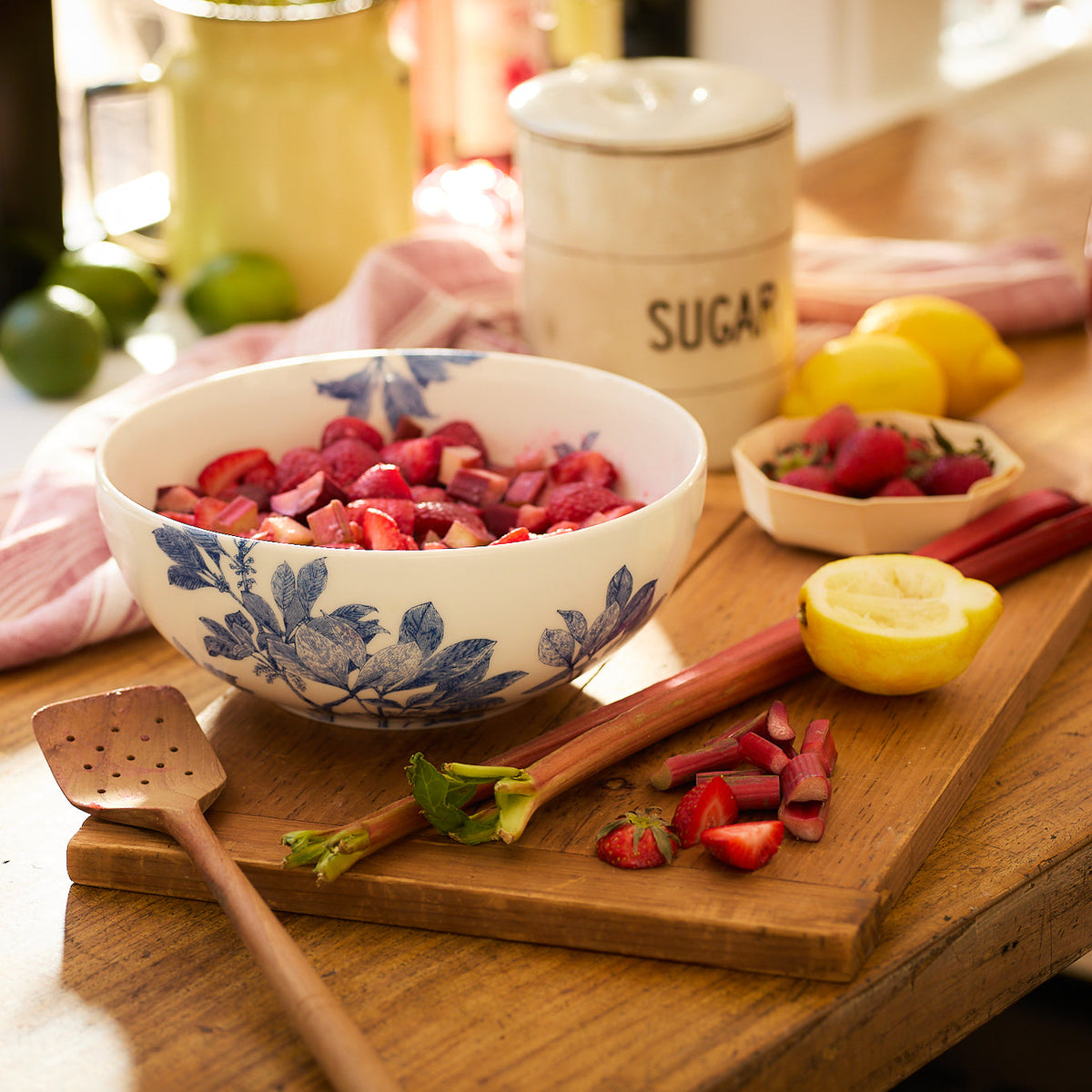 A bowl of chopped rhubarb and strawberries, with lemon and sugar nearby, is ready to serve in the Caskata Arbor Serving Set.