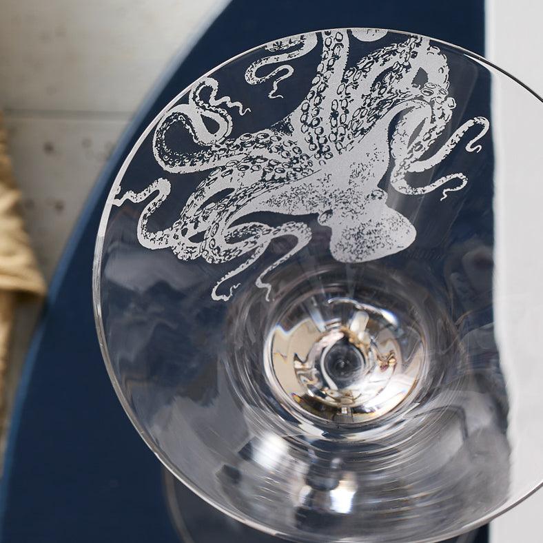 A close-up view of Lucy Martini Glasses by Caskata Artisanal Home with an intricate illustration of an octopus, created using the sand-etching technique.