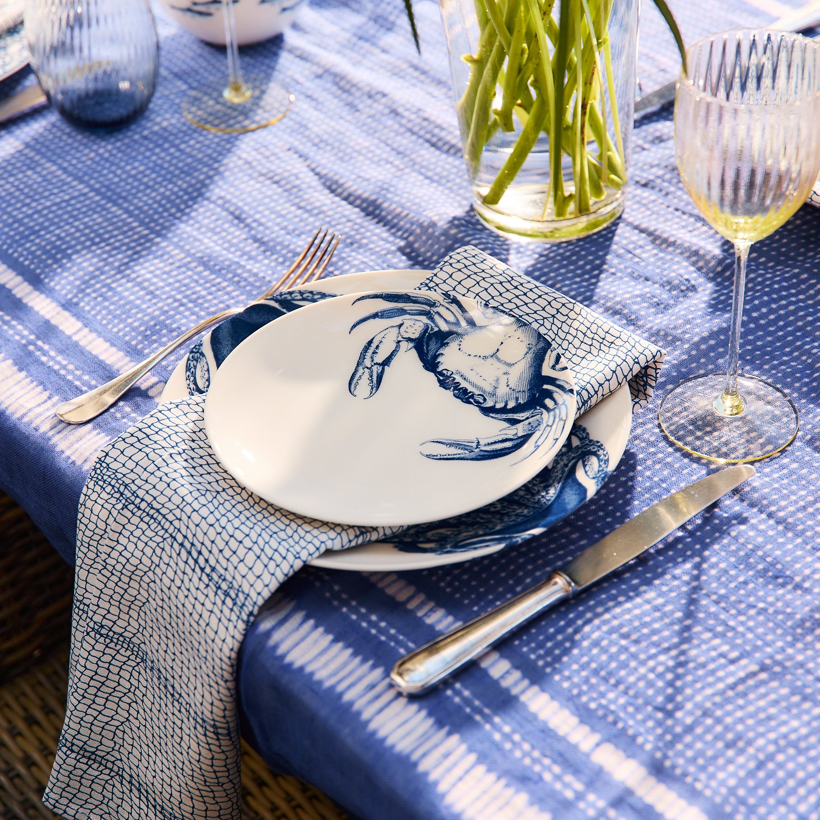 A stack of five folded Catch Dinner Napkins, Set of 4 by Caskata with a blue coastal pattern.