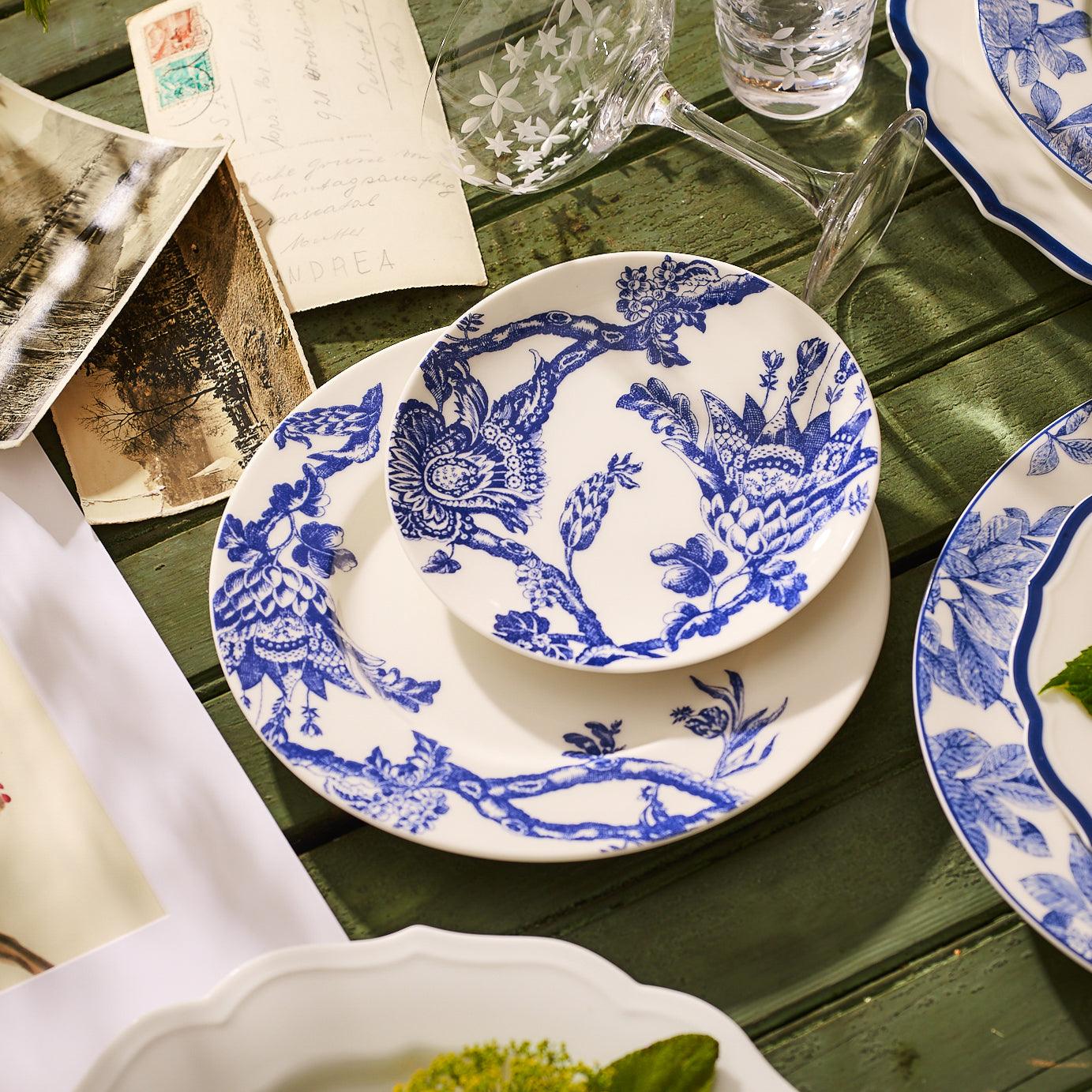 A white ceramic plate with a blue floral and branch design along the rim, this premium porcelain Arcadia Rimmed Salad Plate is part of the exquisite Caskata Artisanal Home dinnerware collection.