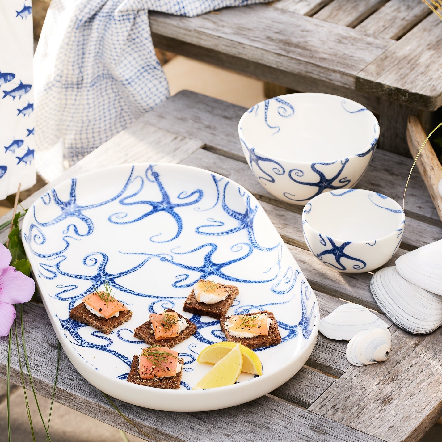Introducing the Starfish Large Coupe Oval Platter by Caskata, a porcelain platter adorned with an enchanting blue octopus design on a pristine white background, ideal for enhancing your entertaining experience.