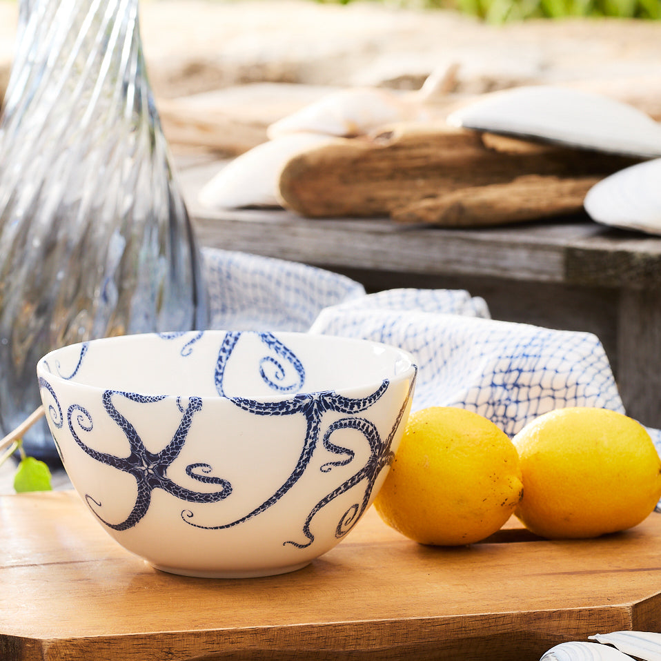 Introducing the Caskata Starfish Cereal Bowl, a white porcelain bowl featuring elegant blue octopus designs, perfect for enjoying your morning cereal.