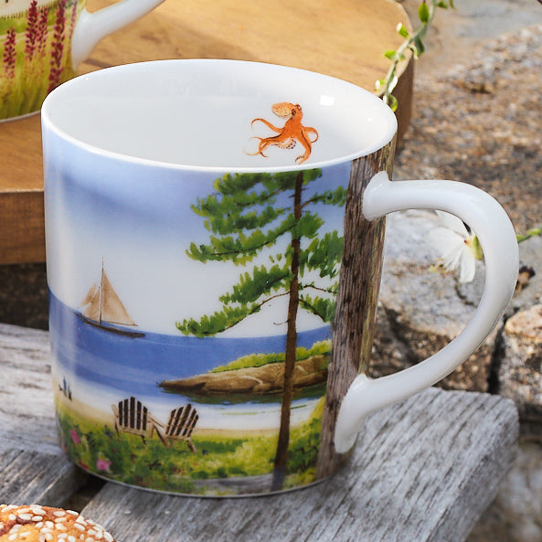 A Caskata X Felix Doolittle By the Sea Mug from the set of 4, crafted in porcelain and showcasing a scenic beach and sailboat design, with a small orange octopus illustration on the rim, inspired by Felix Doolittle's watercolor landscapes.