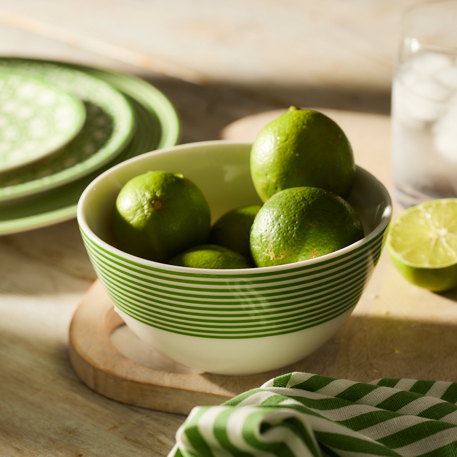 The Newport Stripe Verde Cereal Bowl by Caskata is crafted from high-fired white porcelain and showcases the unique Newport Stripe design with green horizontal stripes around the upper half.