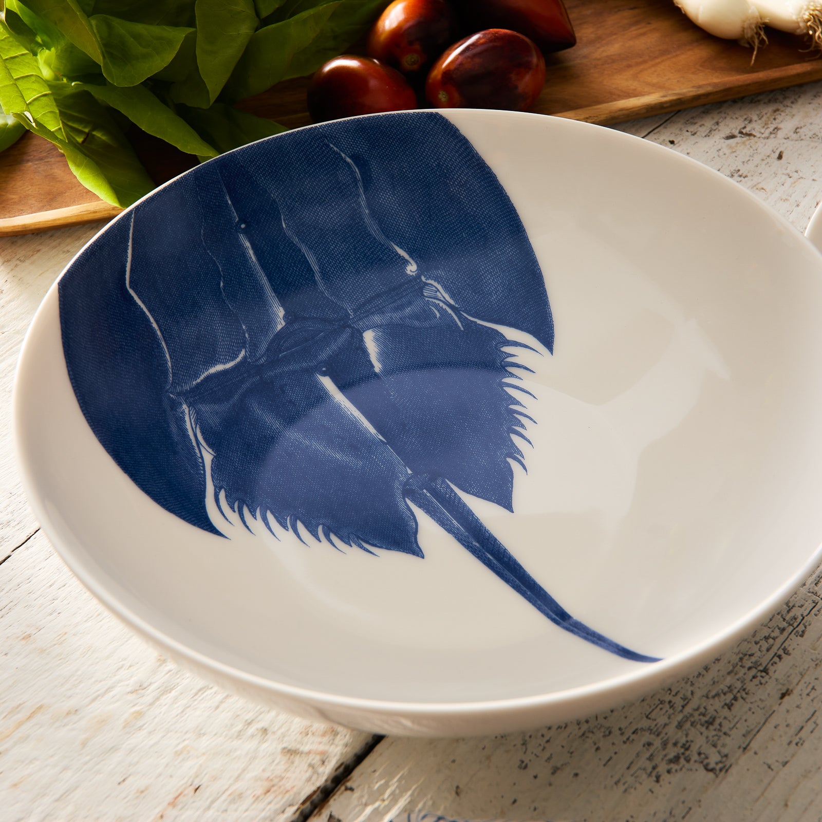 Caskata Artisanal Home's Horseshoe Crab Wide Serving Bowl is crafted from white high-fired porcelain and adorned with a detailed top-view illustration of a blue horseshoe crab.