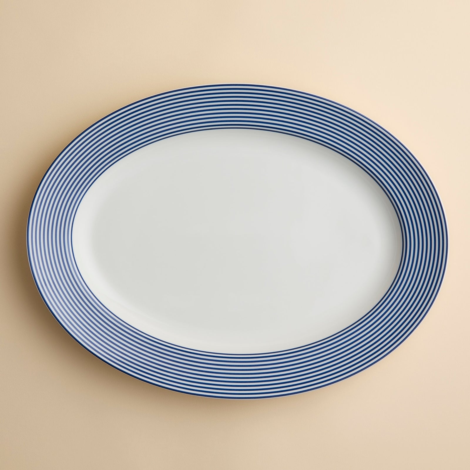 Caskata Newport Stripe Oval Rimmed Platter with a white center and a rim featuring thin blue stripes.