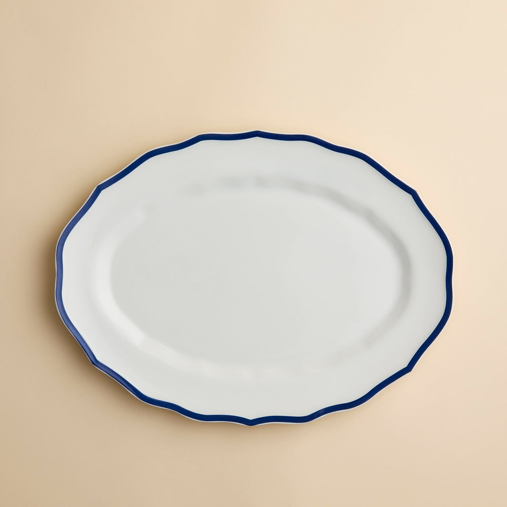 Stella Blue Scalloped Platter, an oval high-fired porcelain platter with a scalloped edge and a dark blue rim.