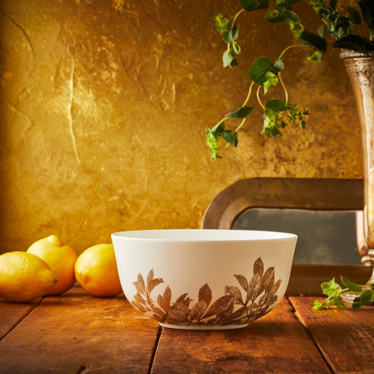 A Gold Arbor Medium Serving Bowl sitting on a table next to lemons.
