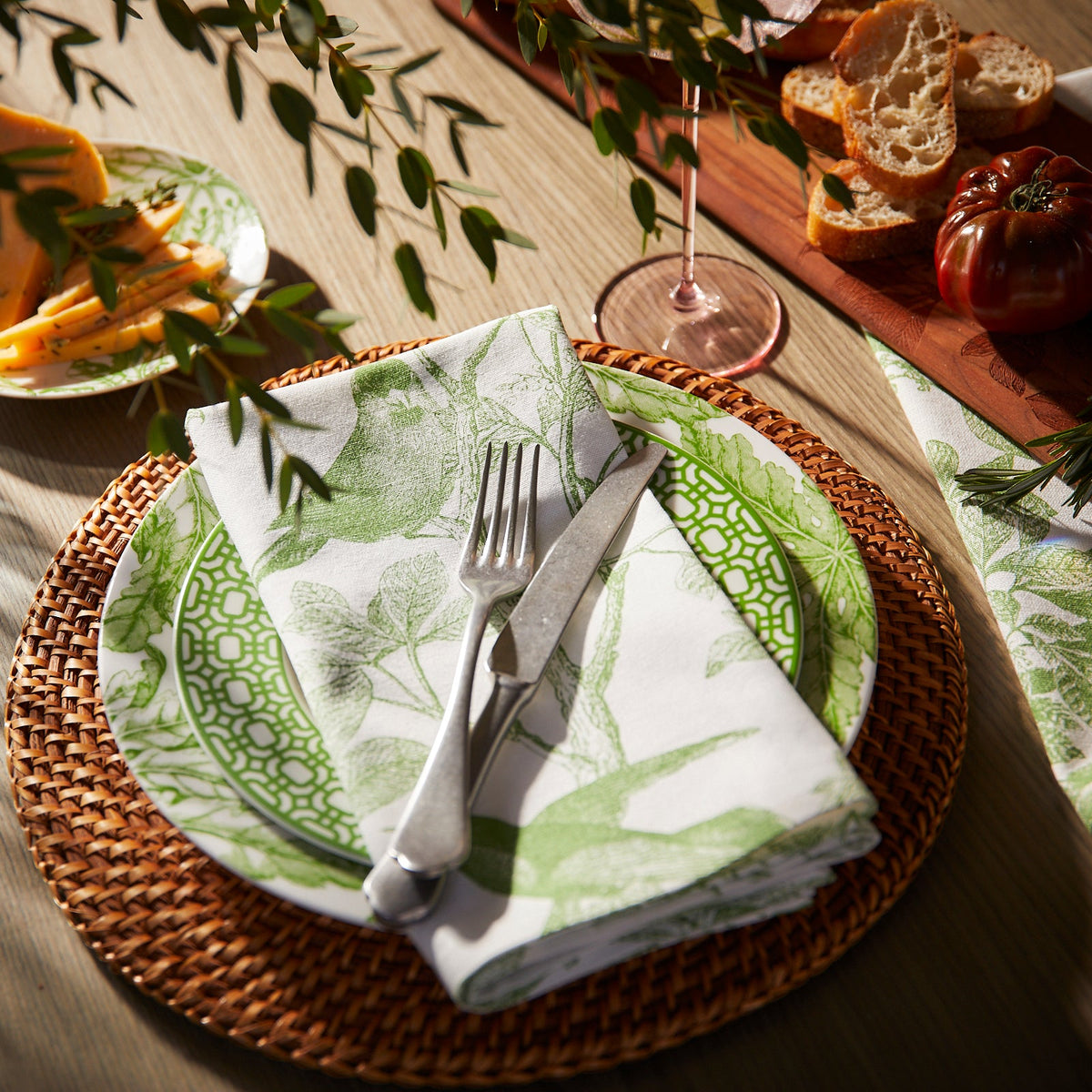 Arbor Birds Green Oversized Dinner Napkin in 100% Cotton Shown on a Table with Freya and Newport Garden Gate dinnerware from Caskata