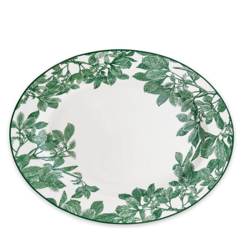 The Arbor Green Oval Rimmed Platter by Caskata Artisanal Home is a round white porcelain piece featuring a contemporary green leaf pattern along the border, seamlessly blending classic and modern high style.