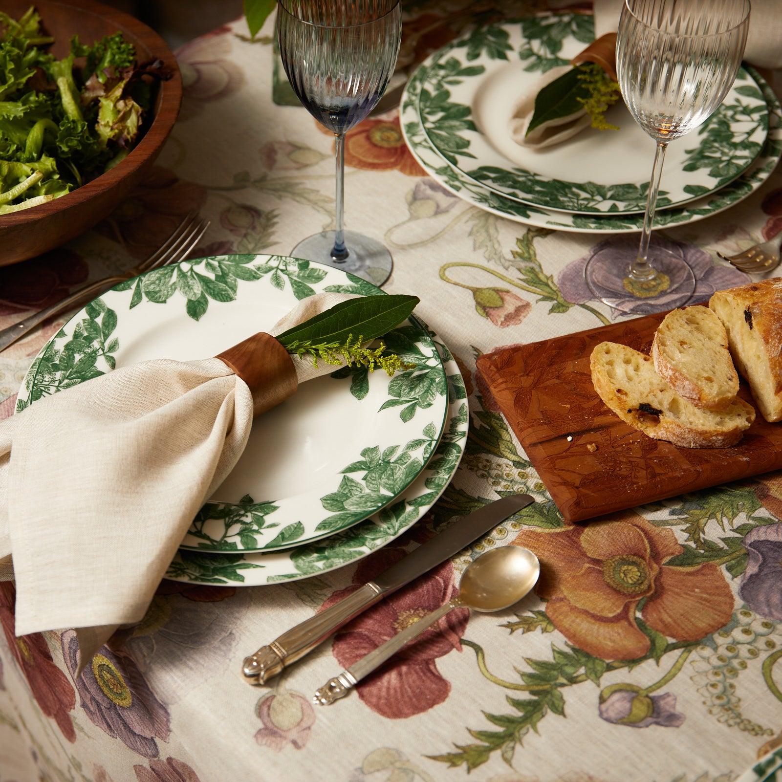 The Caskata Arbor Green Table for 8 is a porcelain dinnerware set of twelve white plates with green leaf patterns in three sizes, arranged by size. This collection is dishwasher and microwave safe for everyday use.
