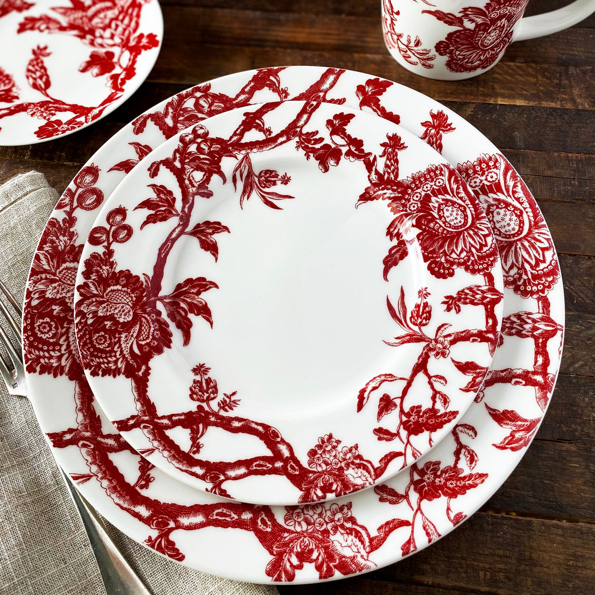 Arcadia Crimson Dinnerware from Caskata includes a dinner, salad, canape and mug shown here on a rustic tabletop.