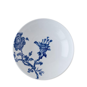 The Arcadia Entrée Bowl by Caskata Artisanal Home features a white ceramic finish with a blue floral and branch design on one side, photographed against a white background.