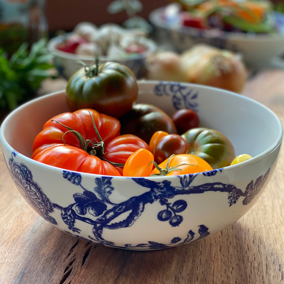 An Arcadia Vegetable Serving Bowl filled with tomatoes and other vegetables by Caskata Artisanal Home.