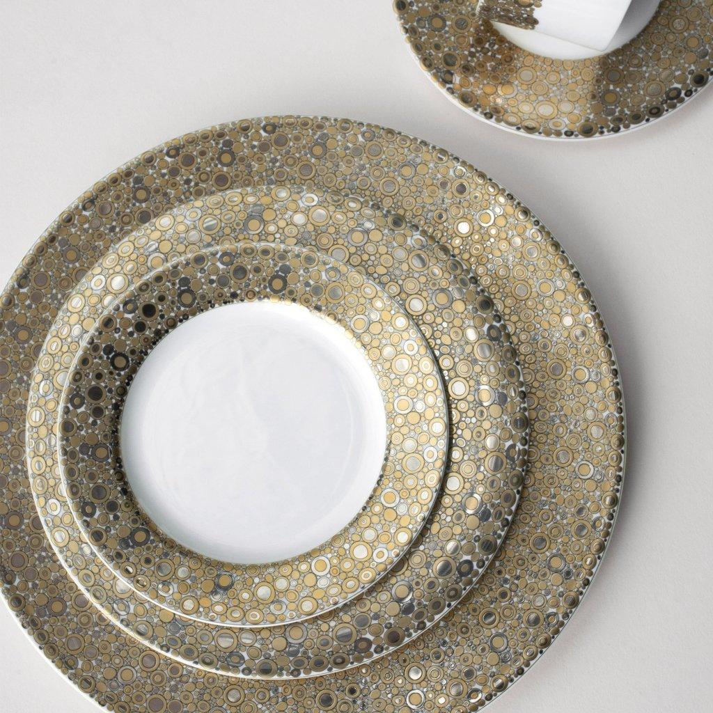 A set of three nested plates, including the Ellington Shimmer Gold &amp; Platinum Bread &amp; Butter Plate by Caskata Artisanal Home and a cup with saucer, all hand-decorated with a gold and silver circular pattern on a white background. This elegant harmony of design is both stunning and practical as each piece is dishwasher safe.