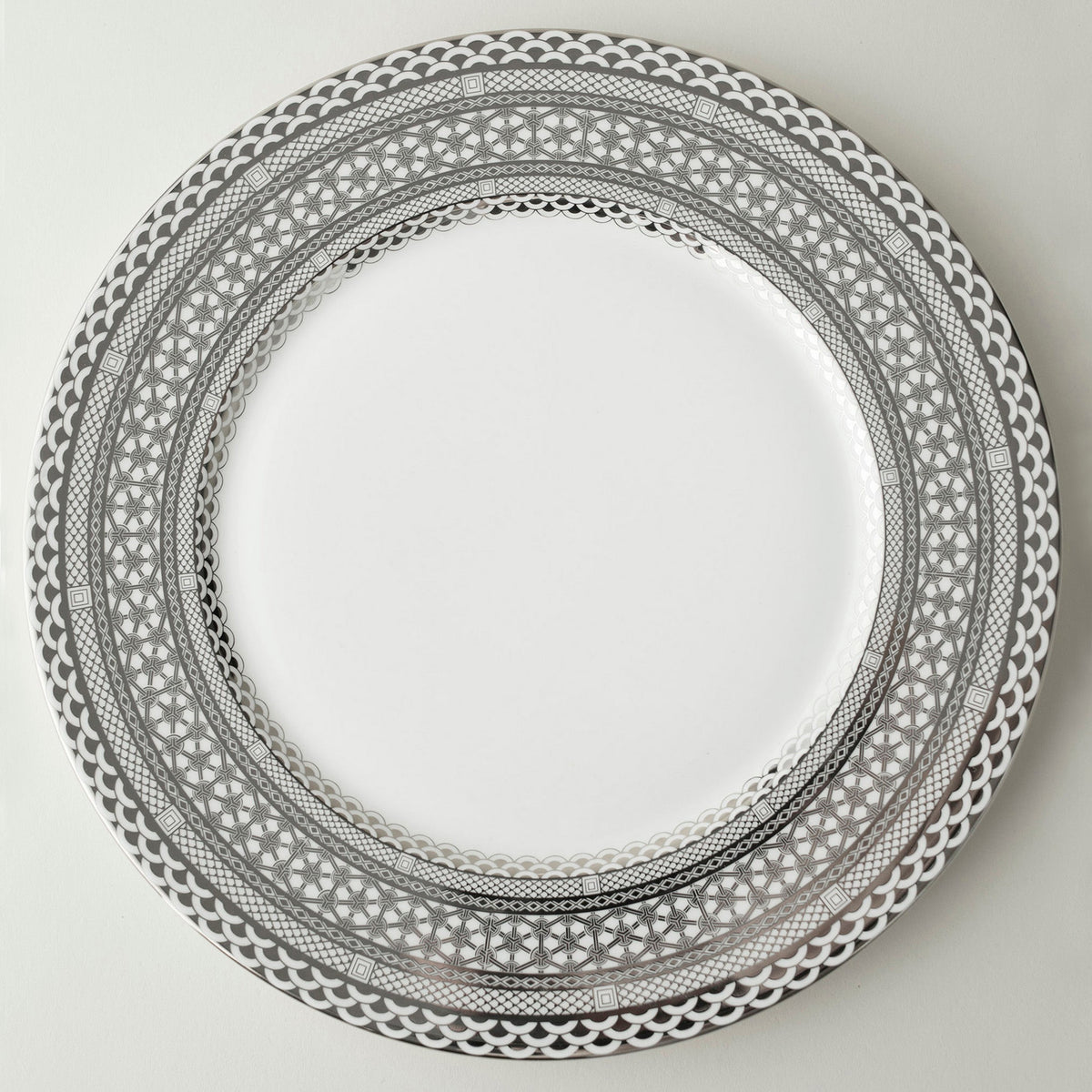 A Caskata Artisanal Home Hawthorne Ice Platinum charger plate with an ornate design on it, made with precious metals.