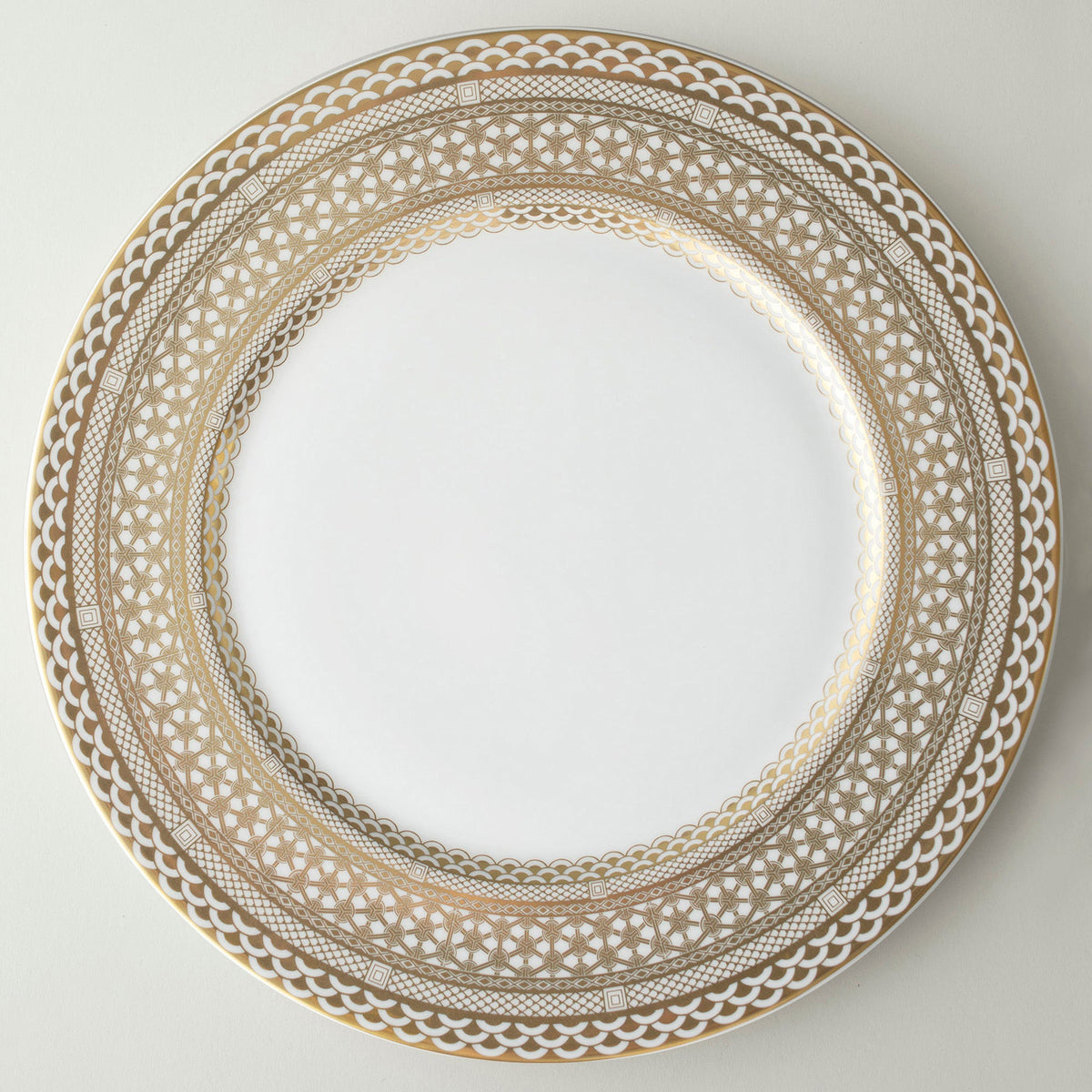 A Caskata Artisanal Home Hawthorne Gilt charger plate, crafted from bone china, featuring a beautiful pattern in gold and white.