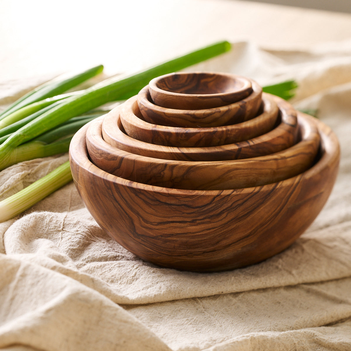 A set of Be Home Olive Wood Nesting Bowls, Set of 6 on a table for kitchen prep.