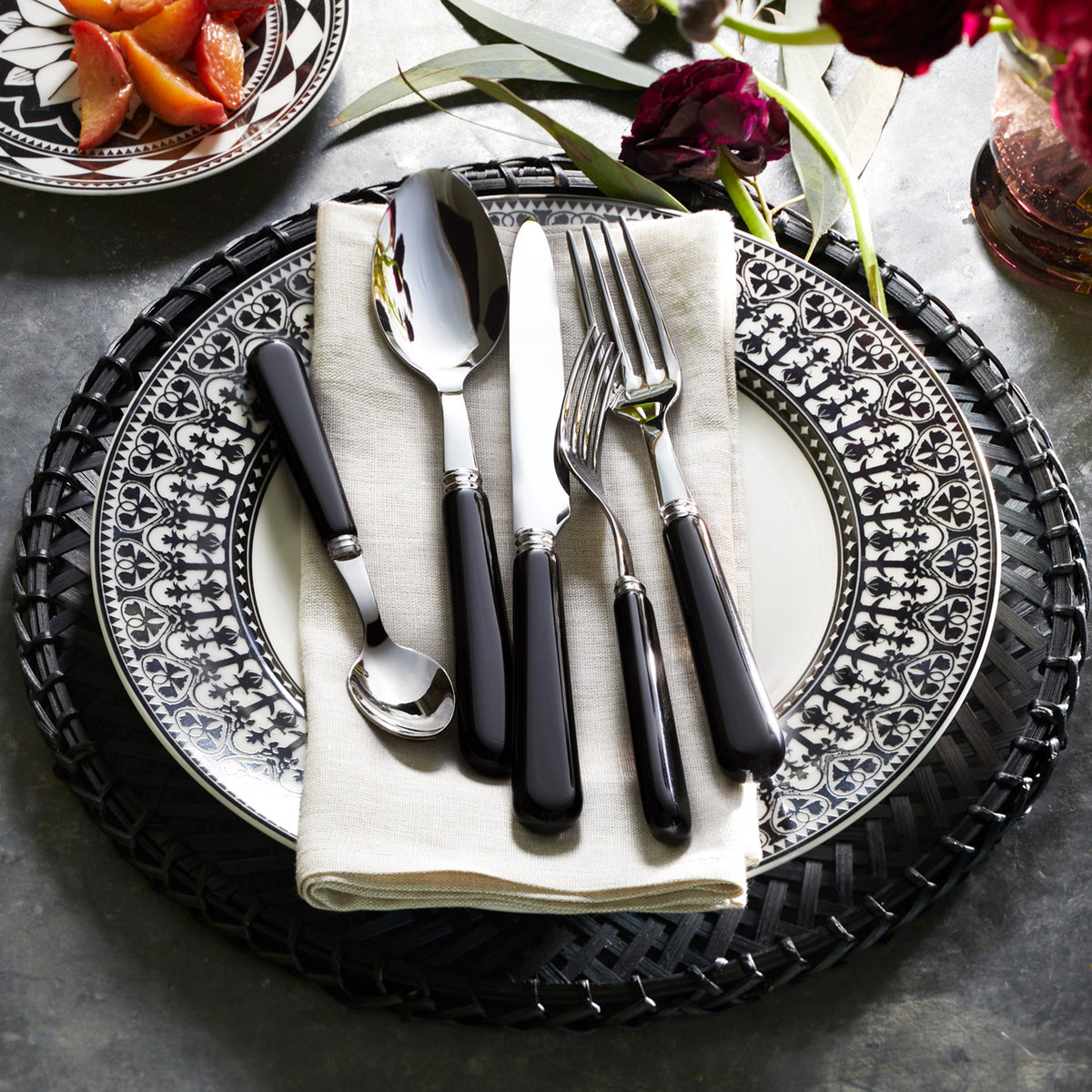 A high-quality Bistro Black 5-Piece Flatware Setting by Sabre with a black and white dinnerware.