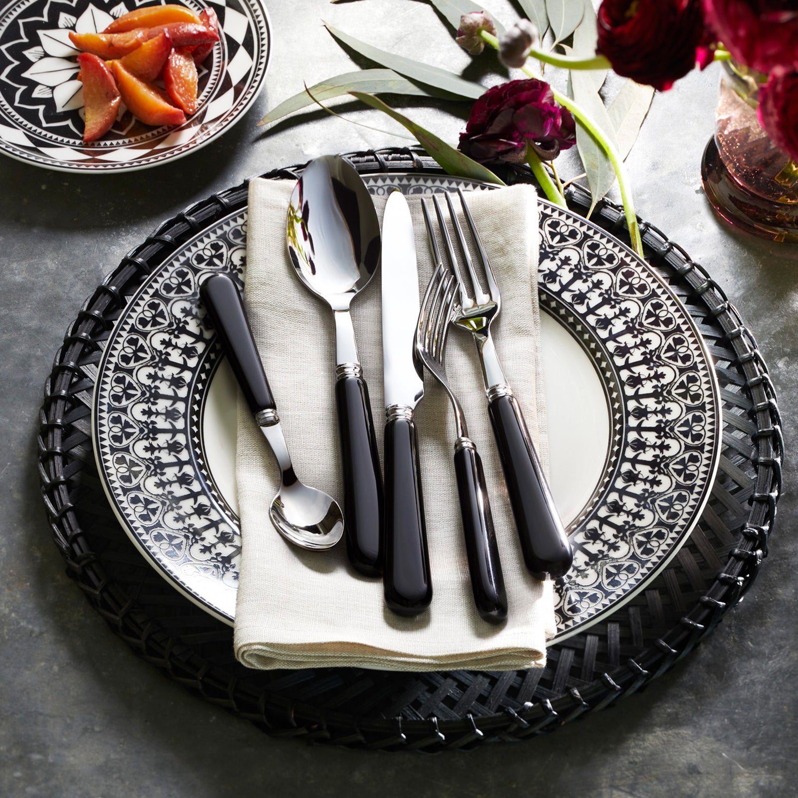 The Caskata Casablanca Table for 8 is a 24-piece porcelain dinnerware set with patterned black and white plates and bowls, displayed in rows on a white background. Dishwasher and microwave safe.