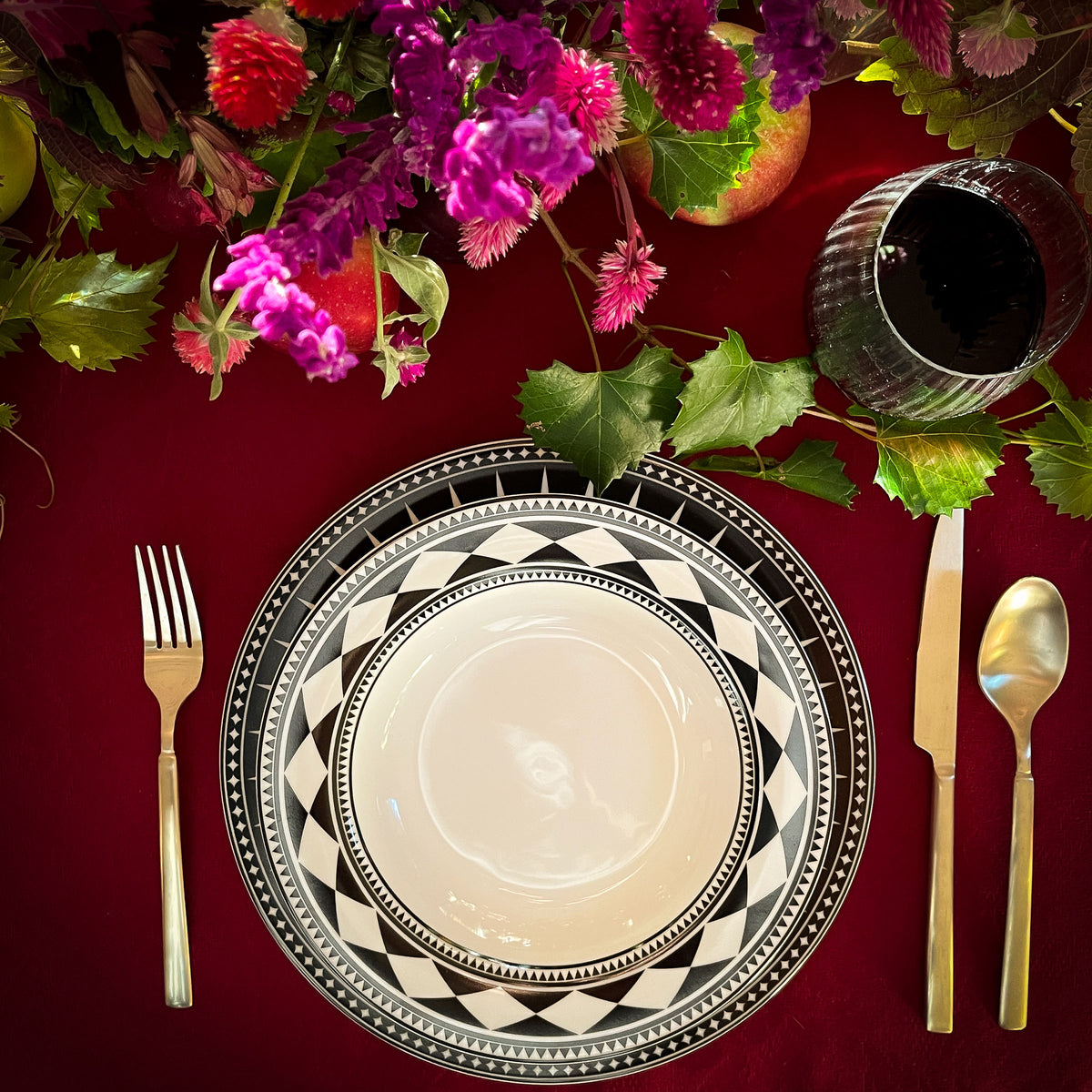 A black and white Fez Rimmed Soup Bowl with flowers on a red cloth, inspired by Moroccan design by Caskata Artisanal Home.