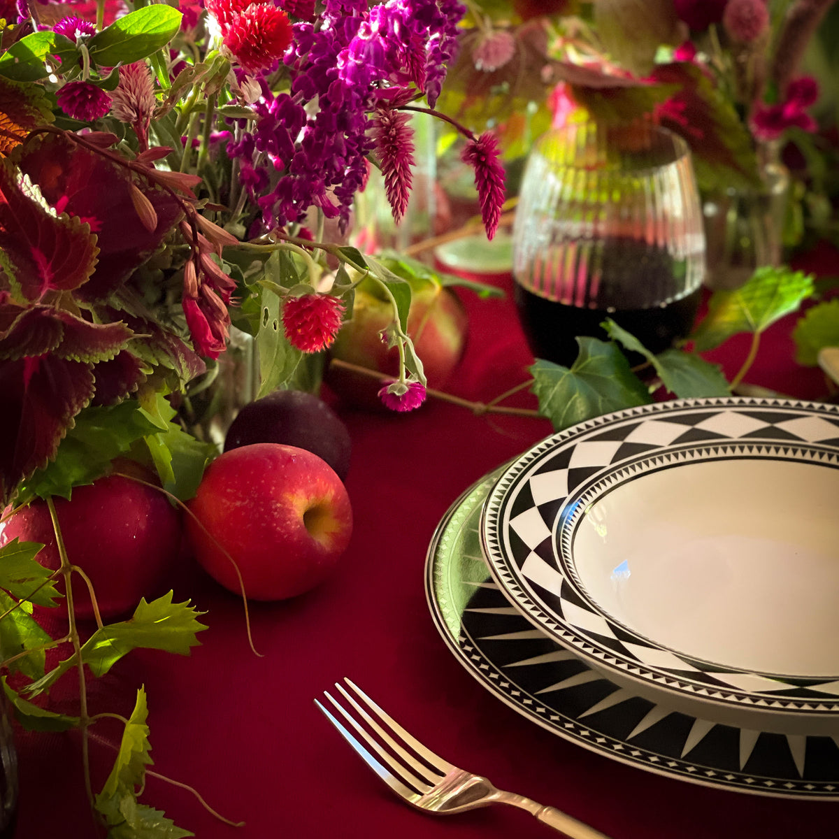 Moroccan-inspired black and white table setting with flowers, fruit, and a Caskata Artisanal Home Fez Rimmed Soup Bowl.