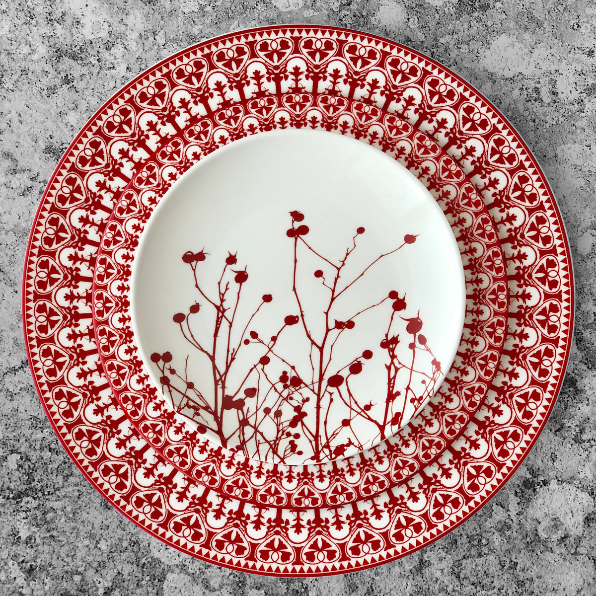 A Casablanca Crimson Rimmed Dinner Plate with festive-colored berries on it, inspired by Caskata Artisanal Home dinnerware.
