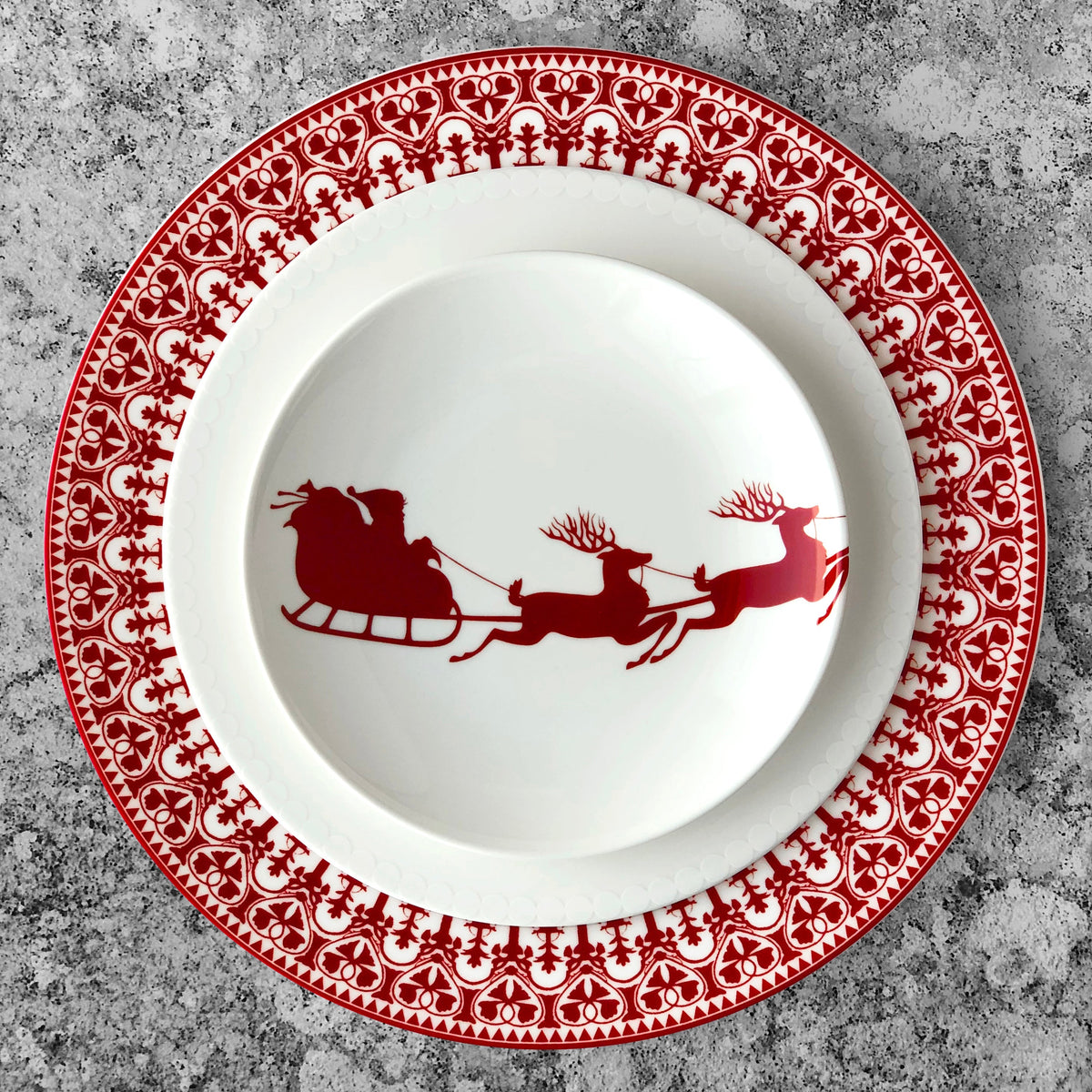 A Casablanca Crimson Rimmed Dinner Plate by Caskata Artisanal Home featuring a sleigh and reindeer on it, with a touch of festive color in crimson. Made from premium porcelain dinnerware.