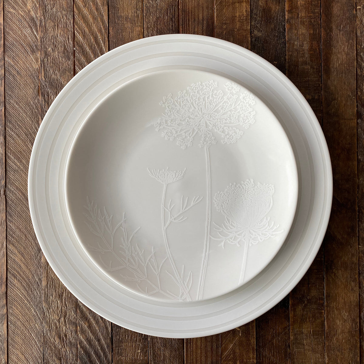 A crisp Cambridge Stripe White Rimmed Dinner plate with dandelions on it by Caskata Artisanal Home.