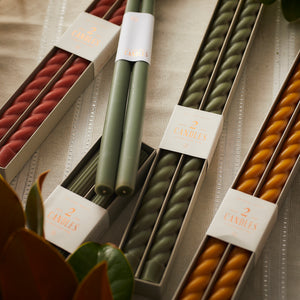 A set of Floral Society moss green candles with a floral design in a box on a table.