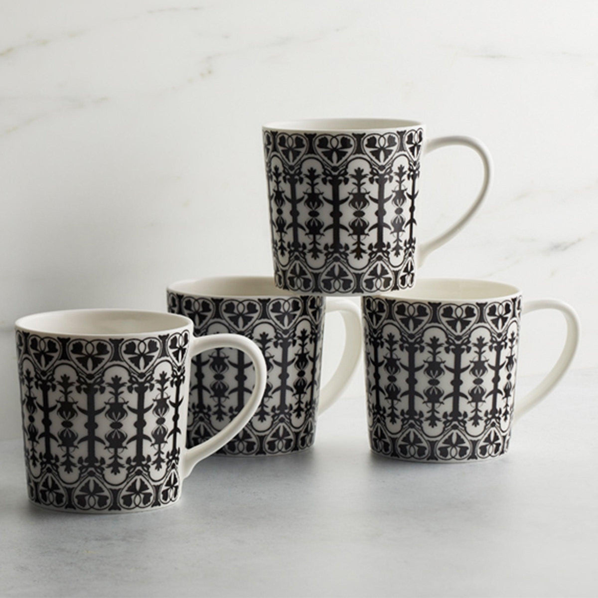 Four black and white Caskata Artisanal Home Casablanca mugs on a marble surface.