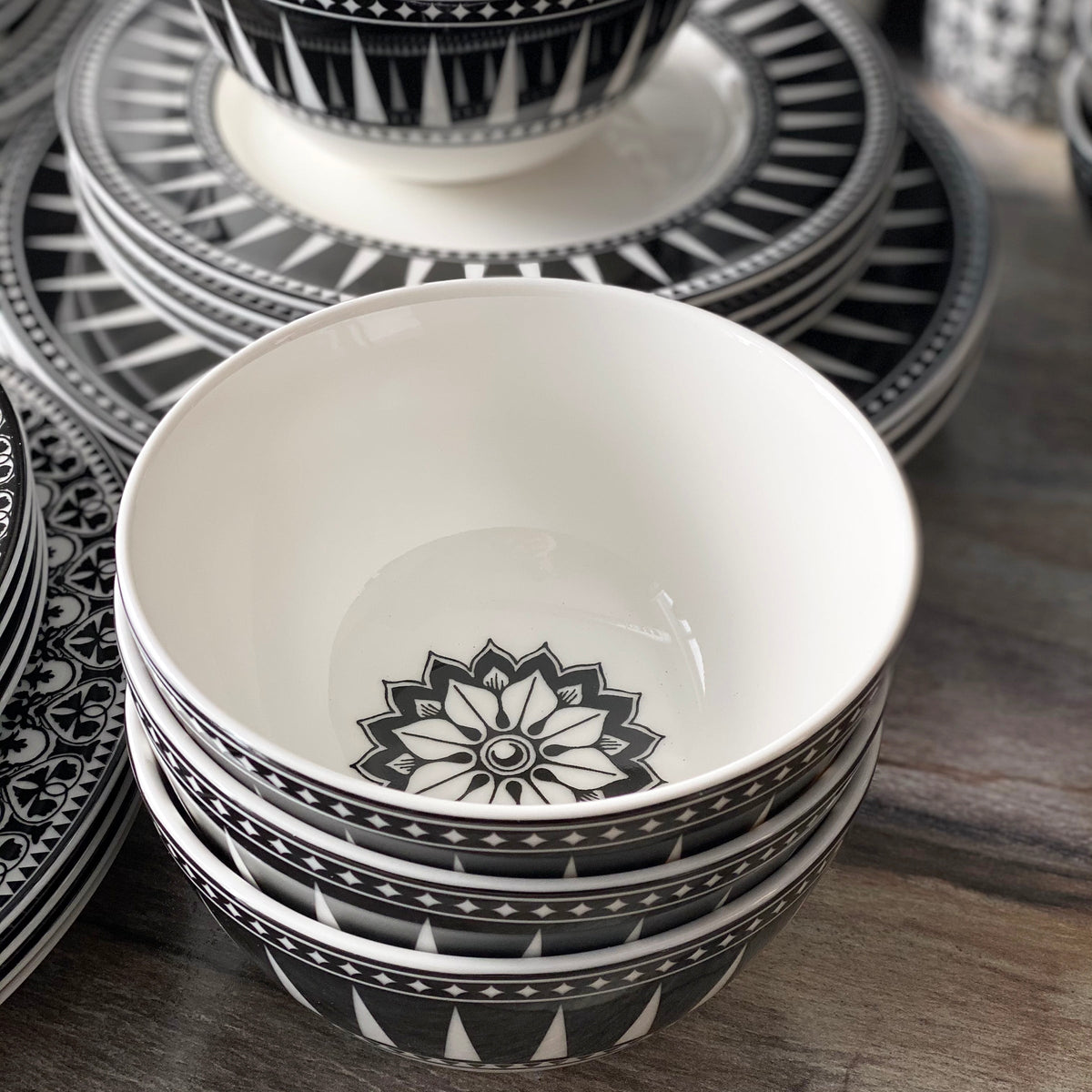 A Geometrics Collection 60 Pc. Set of black and white plates and bowls by Caskata Artisanal Home on a table.