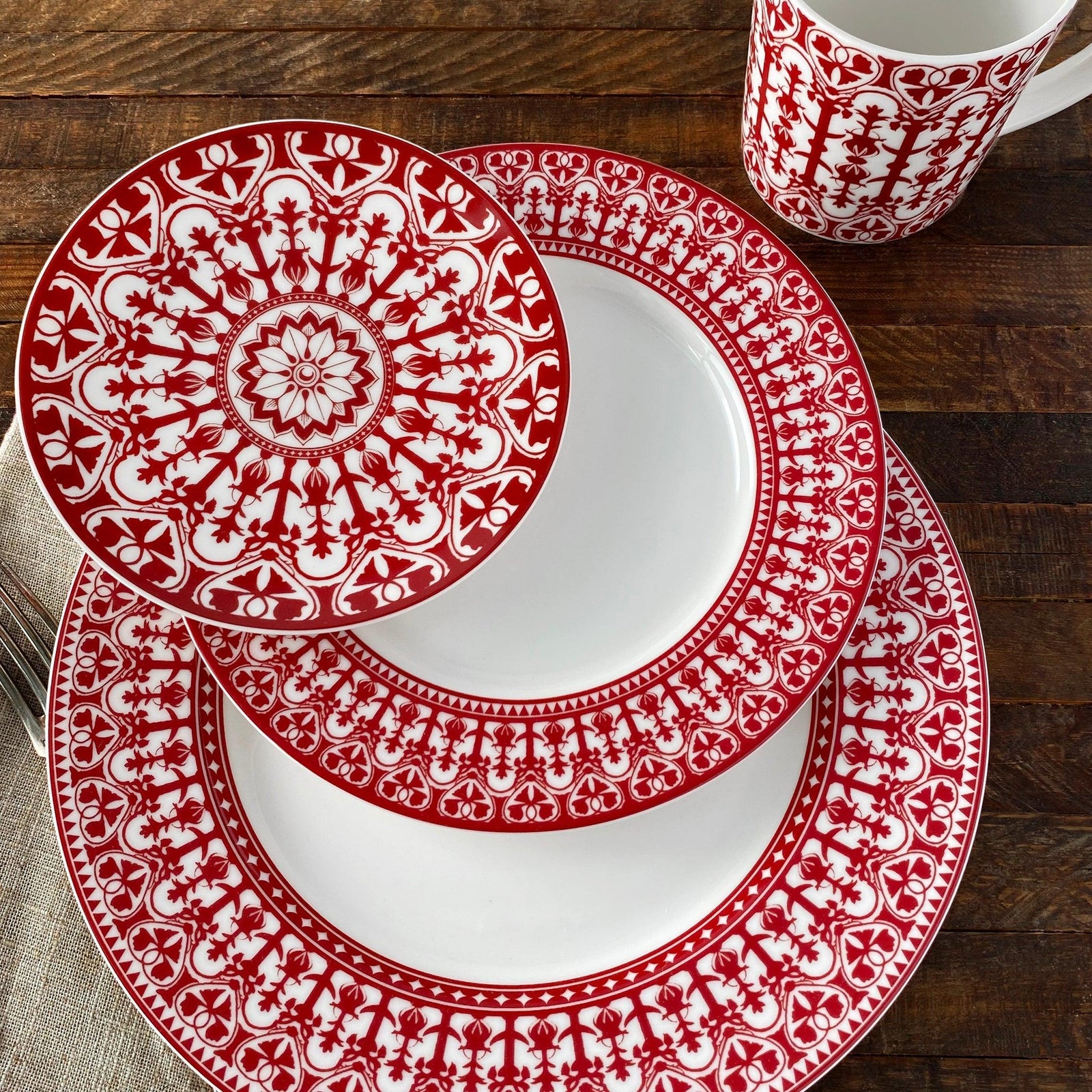 Four round plates with intricate red and white floral patterns, reminiscent of heirloom-quality **Caskata Artisanal Home's Casablanca Crimson Small Plates**, are arranged together.