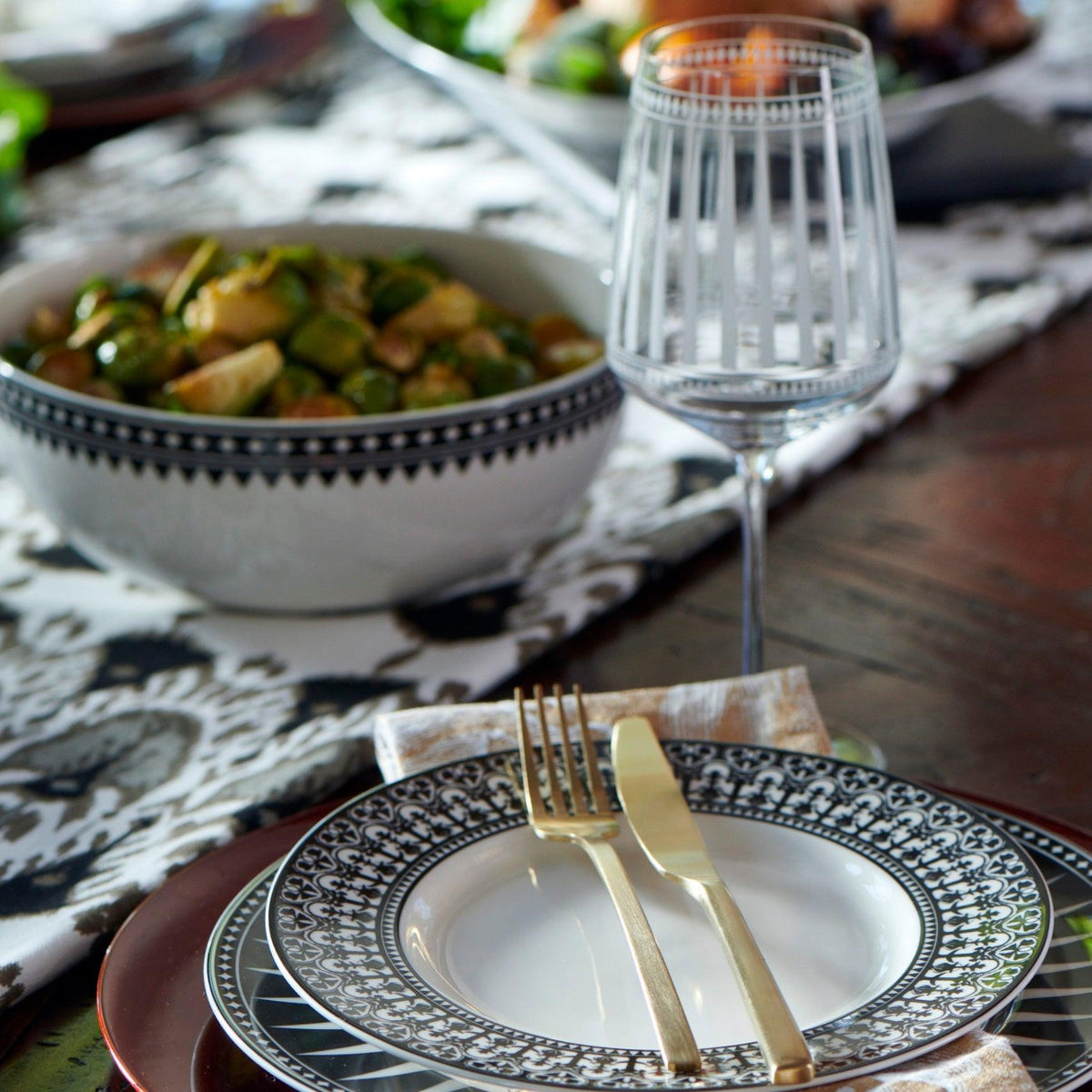 A geometrically inspired Marrakech Vegetable Serving Bowl and fork set elegantly placed on a table, complemented by the vibrant hues of Marrakech. Perfect for serving both casual and formal meals, this Caskata Artisanal Home Geometrics