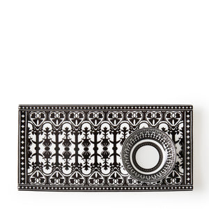 A black and white patterned rectangular plate with an intricately designed cup placed on it, both featuring symmetrical geometric and heart motifs, reminiscent of Caskata's Casablanca Dipping Dishes, Set of 4.