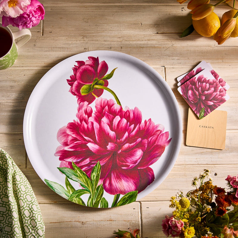 Caskata Pink Peony pattern on white, on a large round birchwood tray with melamine top, set on a wooden table.