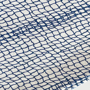 Close-up of 100% cotton fabric with an irregular blue grid pattern resembling a coastal design. A horizontal blue thread seam runs across the center, perfect for Caskata Catch Dinner Napkins, Set of 4.