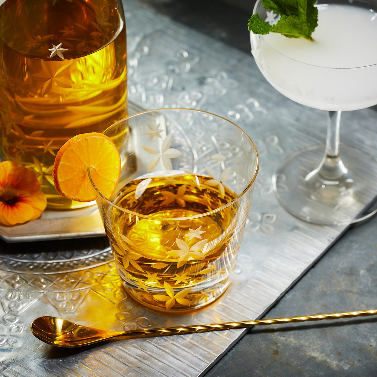 A silver tray with a Chatham Bloom Tumbler by Caskata and a spoon.