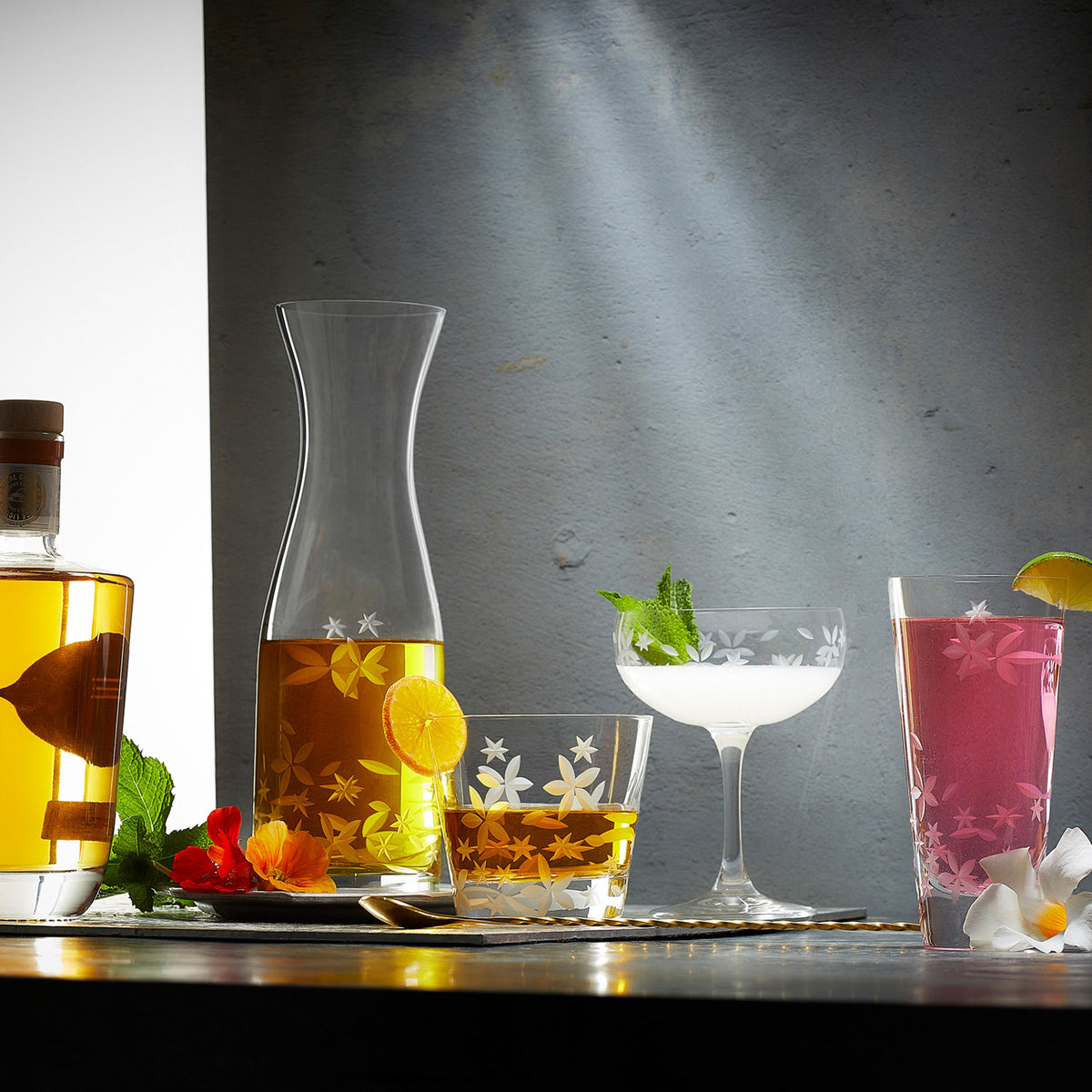 A table adorned with a Caskata Chatham Bloom Carafe filled with a variety of drinks, including the refreshing Bloom blend.