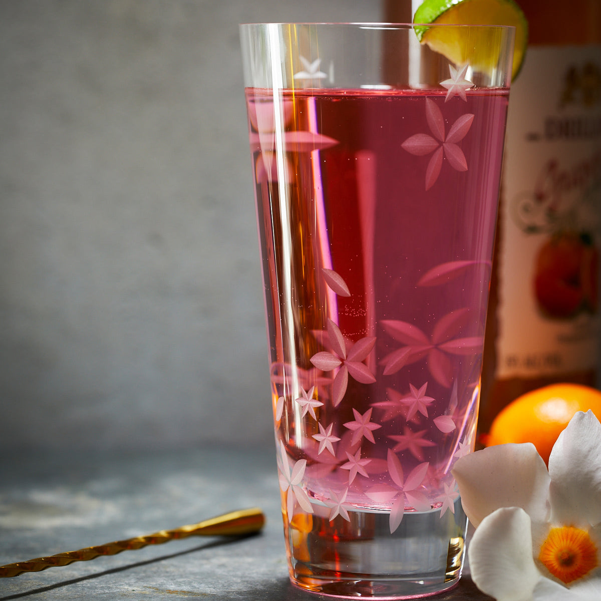 A glass of Chatham Bloom Highball Glasses with oranges and floral pattern by Caskata.