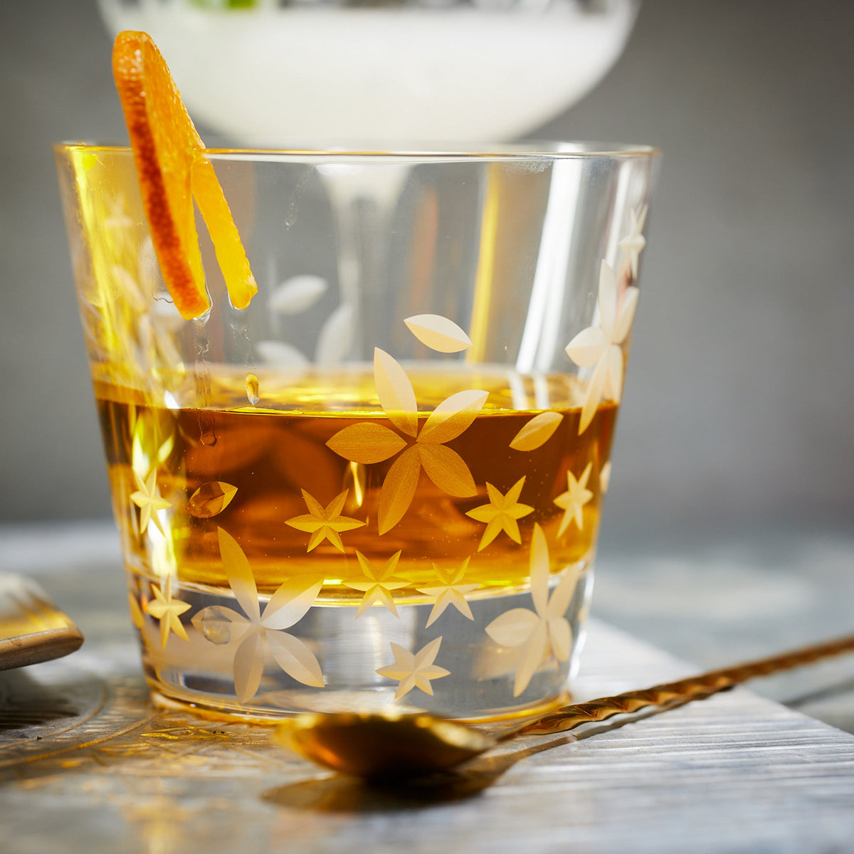 A glass of Caskata Chatham Bloom Tumblers with a retro-shaped orange garnish.