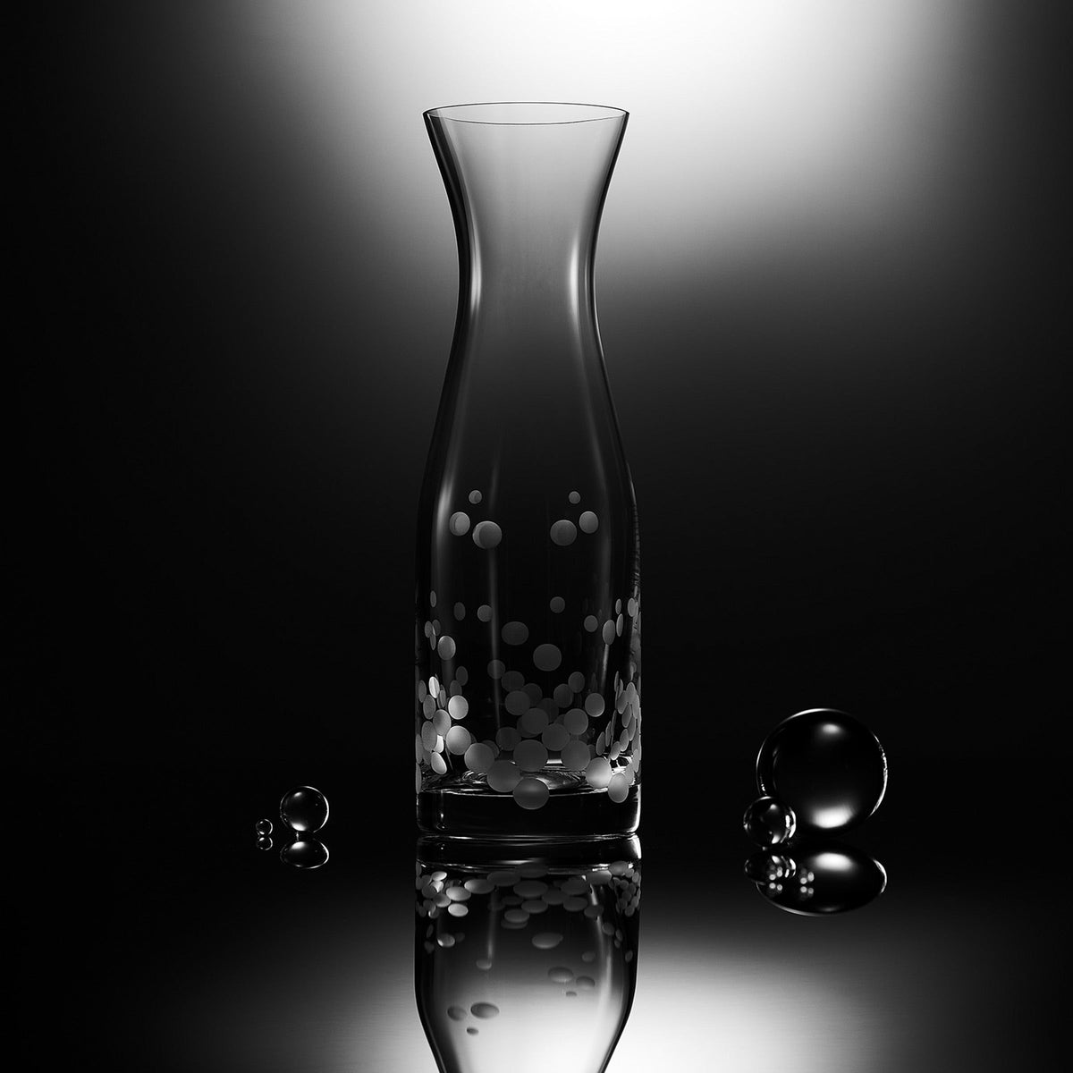 Description: A Caskata Chatham Pop Carafe glass vase with a polka-dot pattern and bubbles in it.