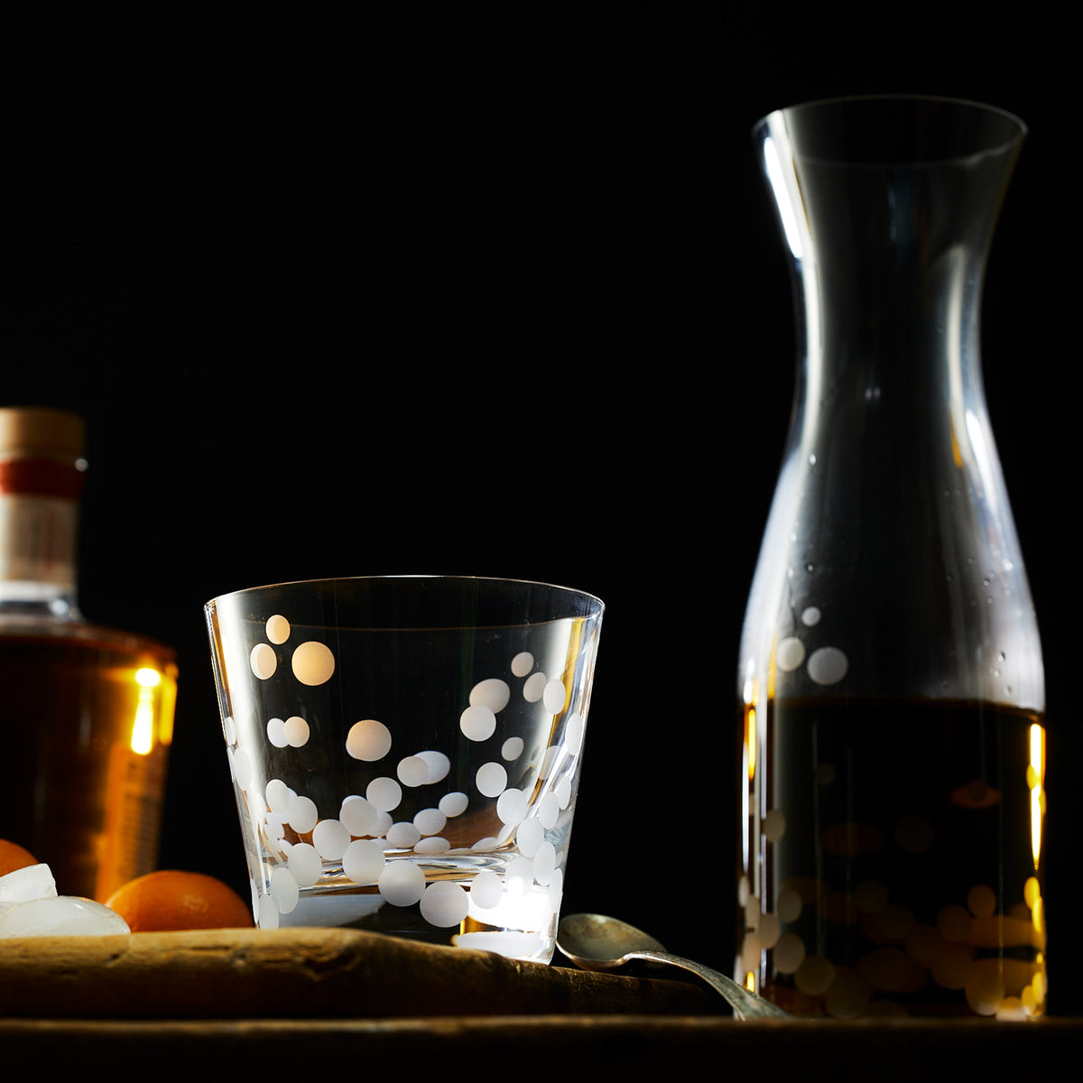 A Caskata Chatham Pop Tumblers glass of wine and a spoon with a retro shapes design on a wooden cutting board.