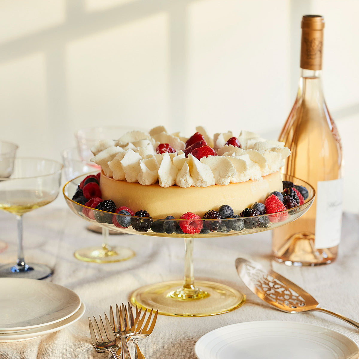 A glamourous Celia Citrine Cake Pedestal with berries beautifully displayed on top, resting upon mouth-blown crystal stands, made by Caskata.