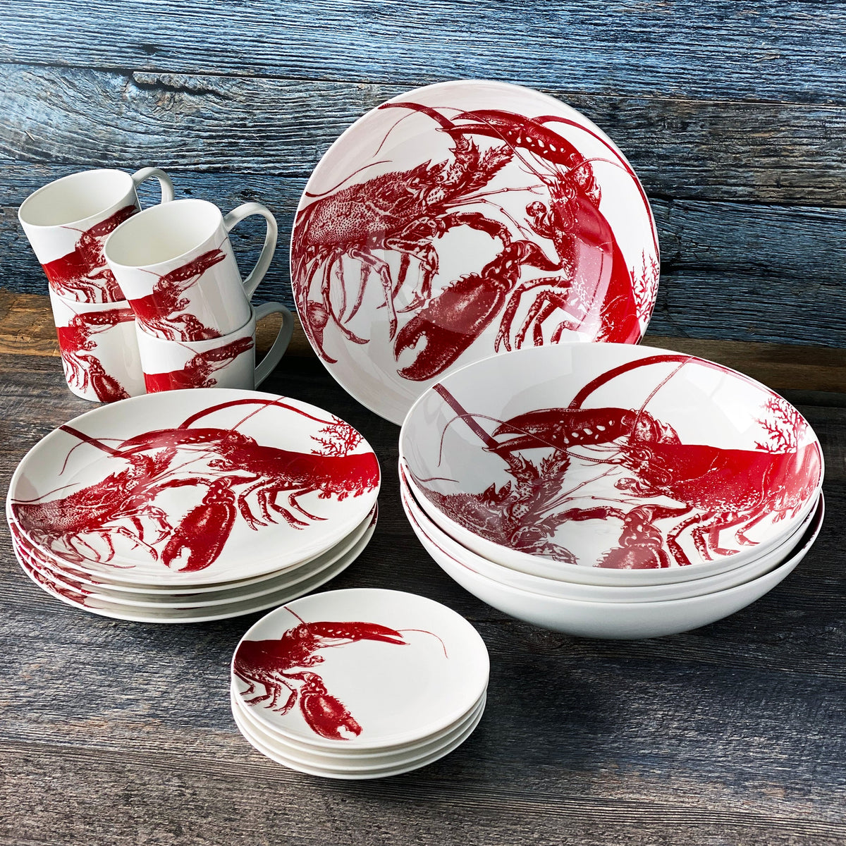 A set of Caskata Artisanal Home Complete Clambake 16 pc. Set lobster plates with lobsters and clam bakes on them.