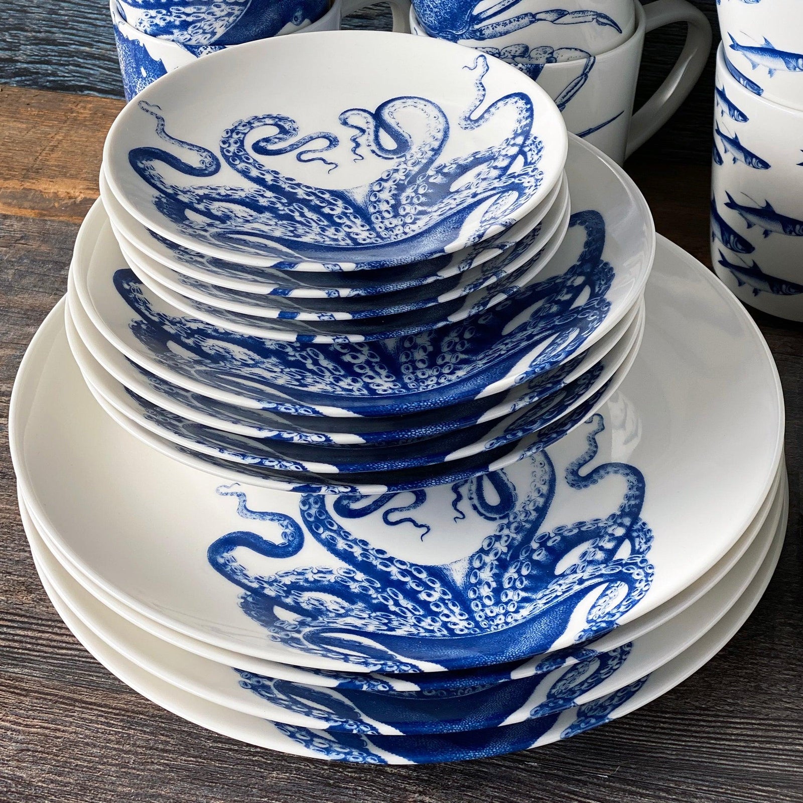 The Caskata Lucy Ultimate Set is a 45-piece porcelain dinnerware collection with blue and white octopus designs on plates, bowls, mugs, and serving dishes, all beautifully arranged on a white background.