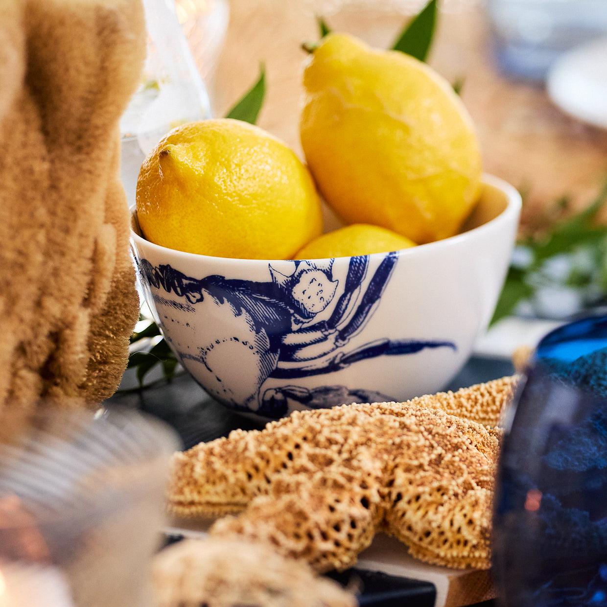 The Caskata Crab Cereal Bowl features a white ceramic base with intricate blue detailing, showcasing an elegant crabs pattern on the exterior.