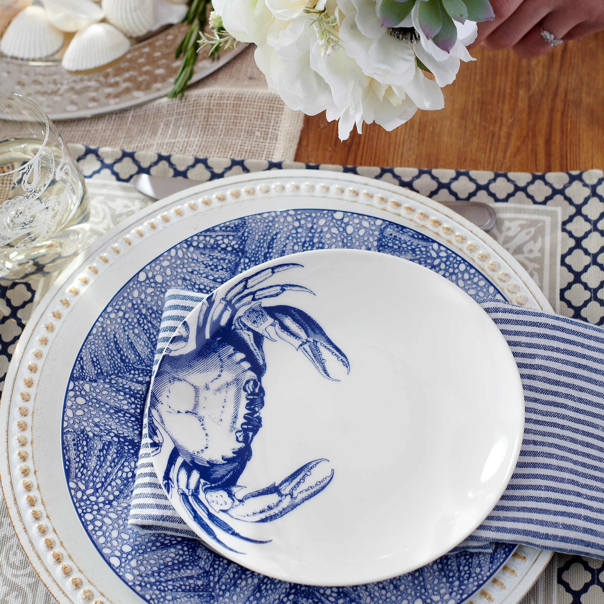 Four heirloom-quality Caskata Artisanal Home Crab Small Plates featuring a charming blue crab pattern on the side are elegantly arranged together.