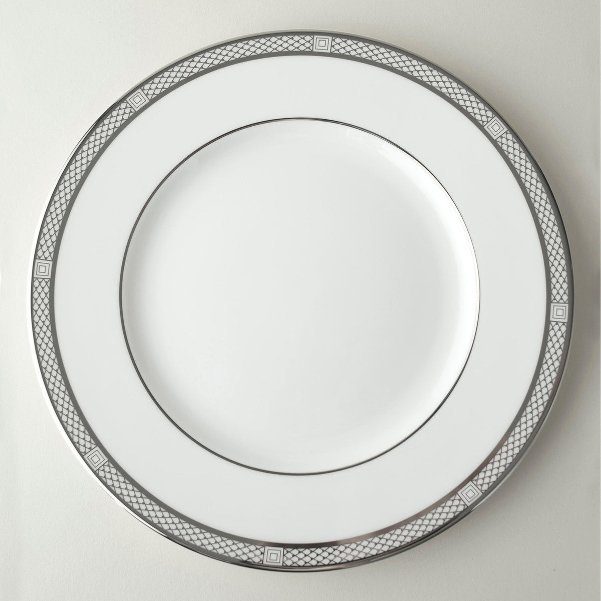A Hawthorne Ice Platinum Simple Dinner Plate by Caskata Artisanal Home on a white marble surface.